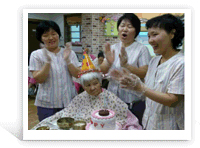 생일을 맞으신 어르신과 축하를 해주고 있는 어르신과 센터 직원의 모습의 사진